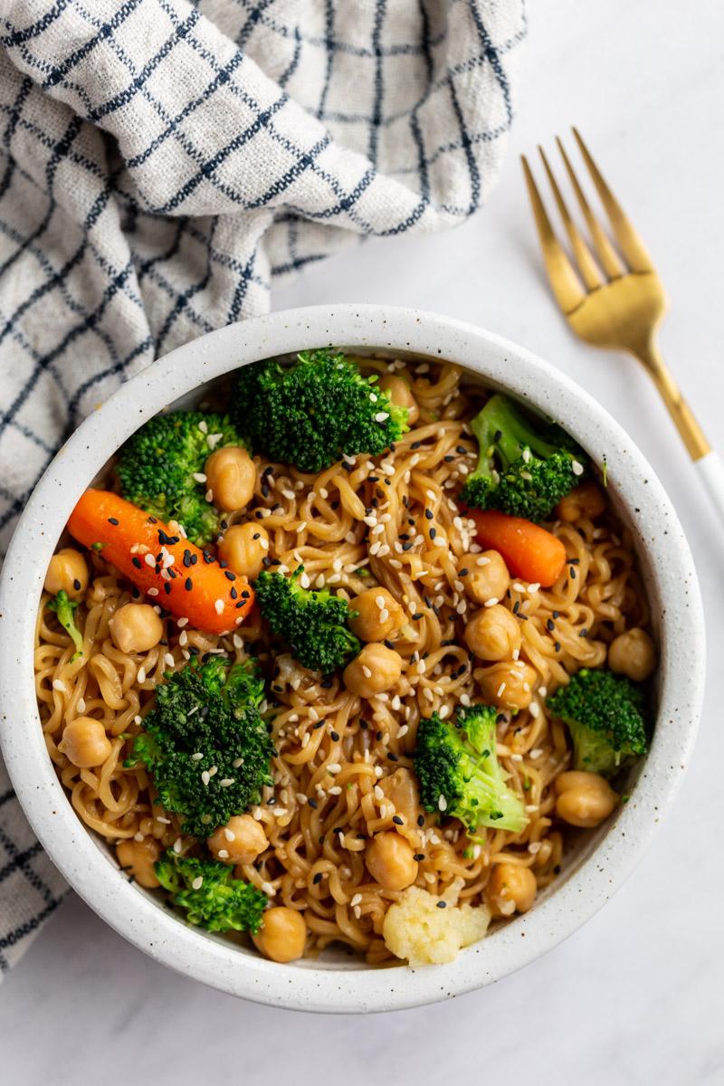 shot of ramen noodles with veggies and sprinkled with sesame seeds. towel in the background