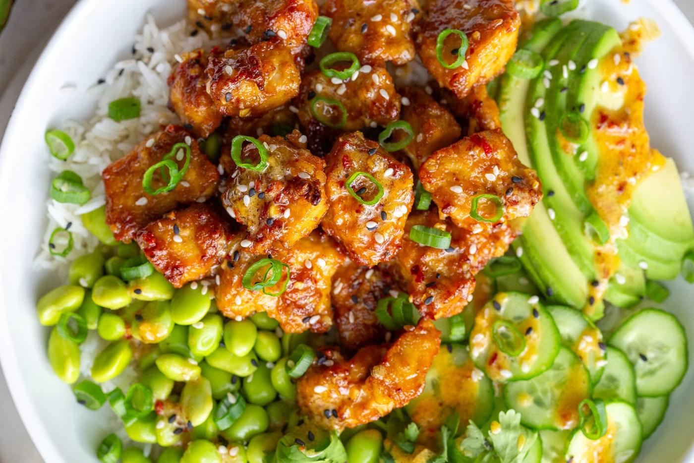 Crispy chili crisp tofu bowls with rice, edamame, avocado, and sesame seeds.