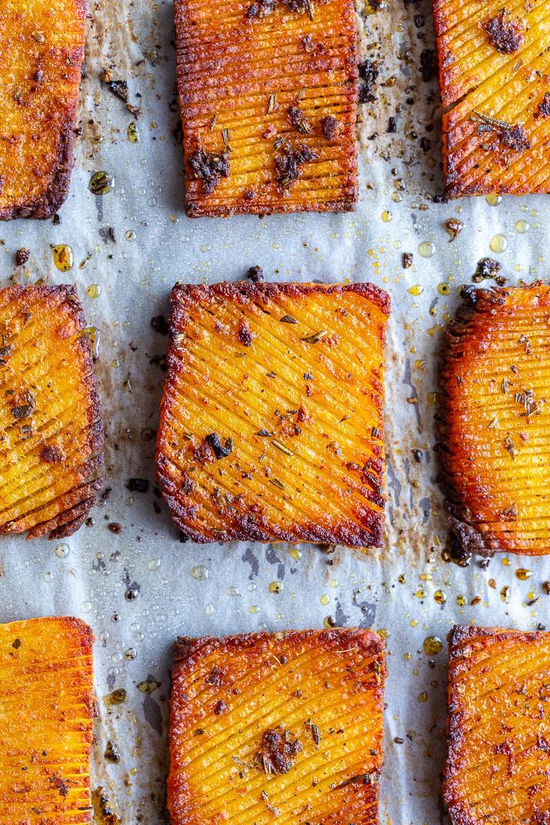 accordion yukon potatoes that are crispy and brown around teh edges and laying on a parchment lined baking sheet