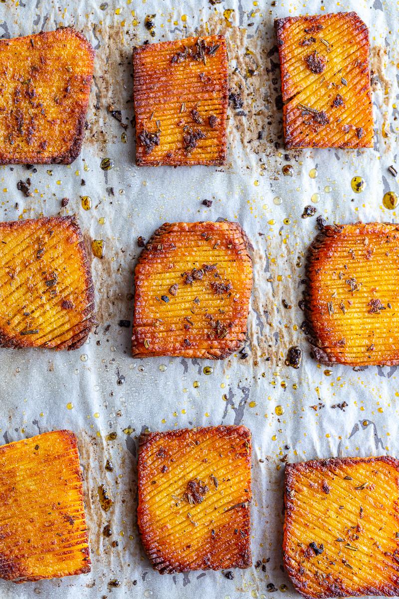 accordion yukon potatoes that are crispy and brown around teh edges and laying on a parchment lined baking sheet