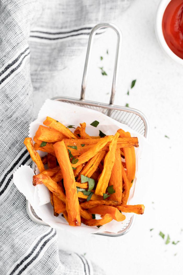 basket lined with parchment paper and filled with carrot fries that have been sprinkled with herbs