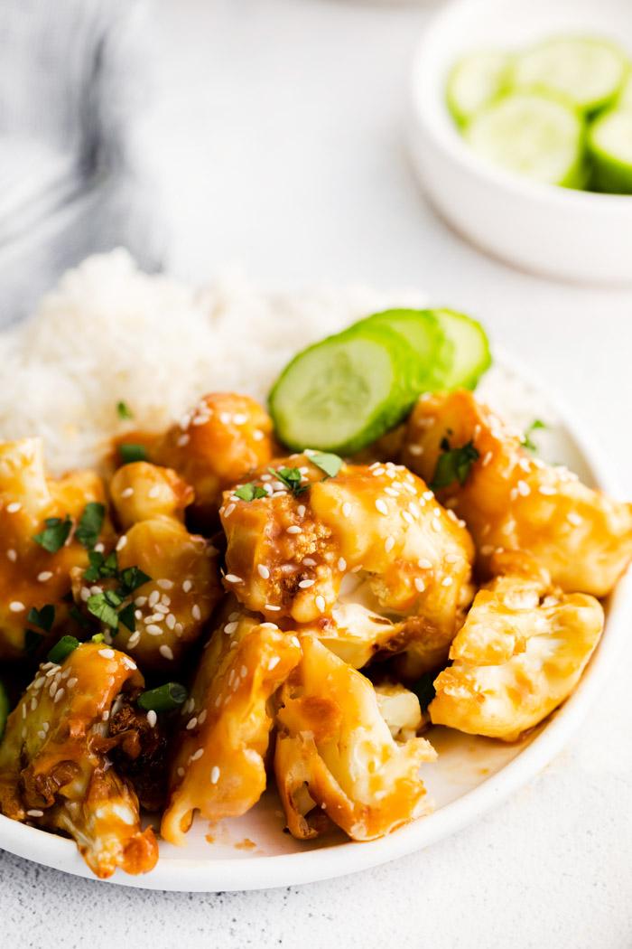 plate filled with white rice, cucumber, and sticky sesame cauliflower