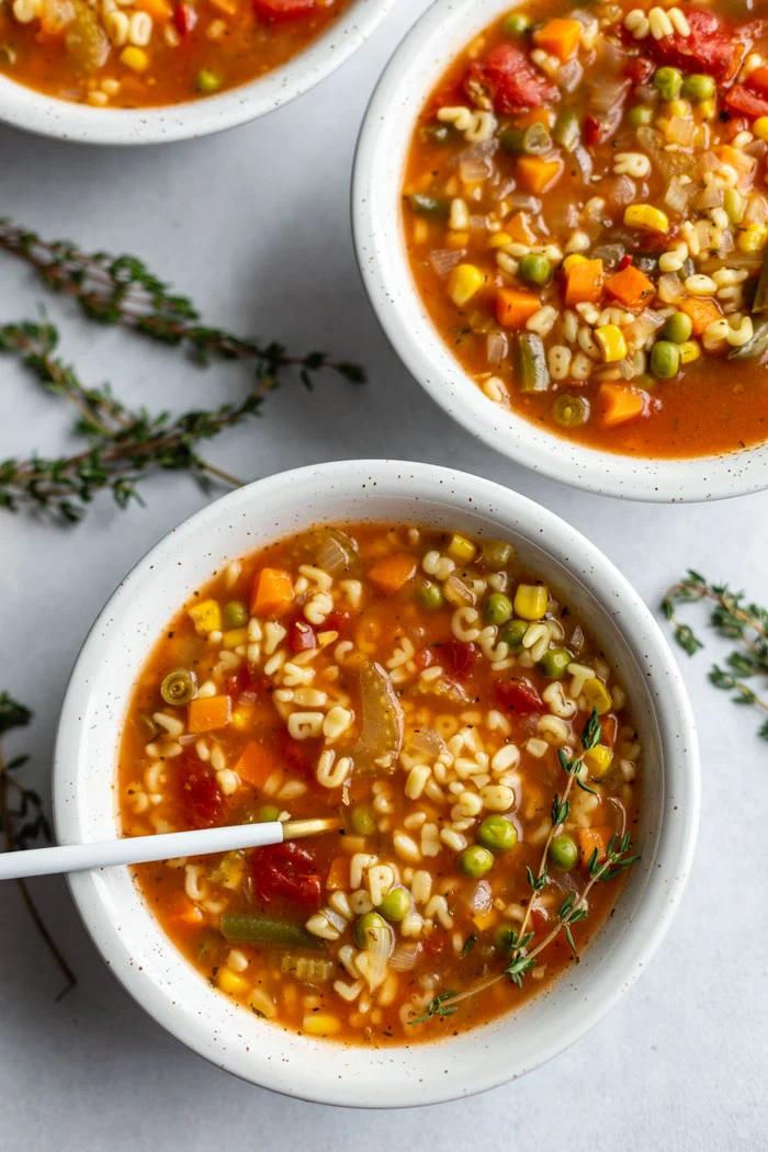 2 bowls of alphabet vegetable soup with a spoon on one bowl
