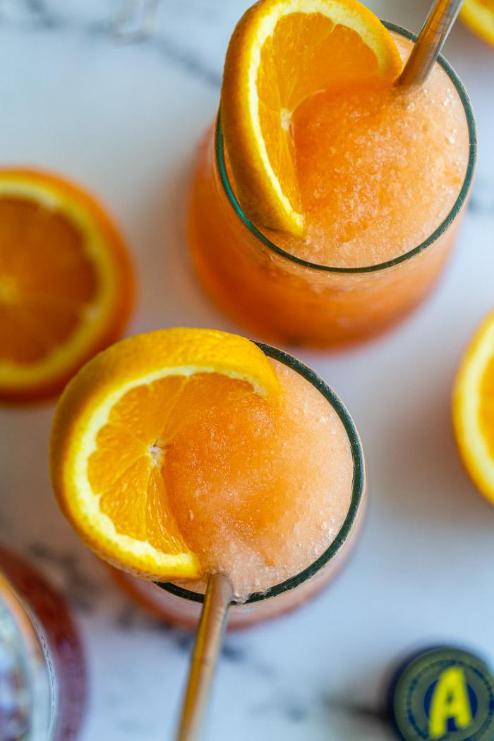 top down shot of 2 frozen aperol spritz cocktails with orange slices in them