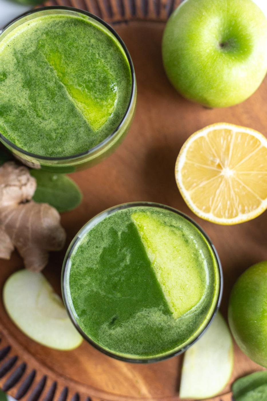 green juice in a small glass with another glass in the corner of the shot
