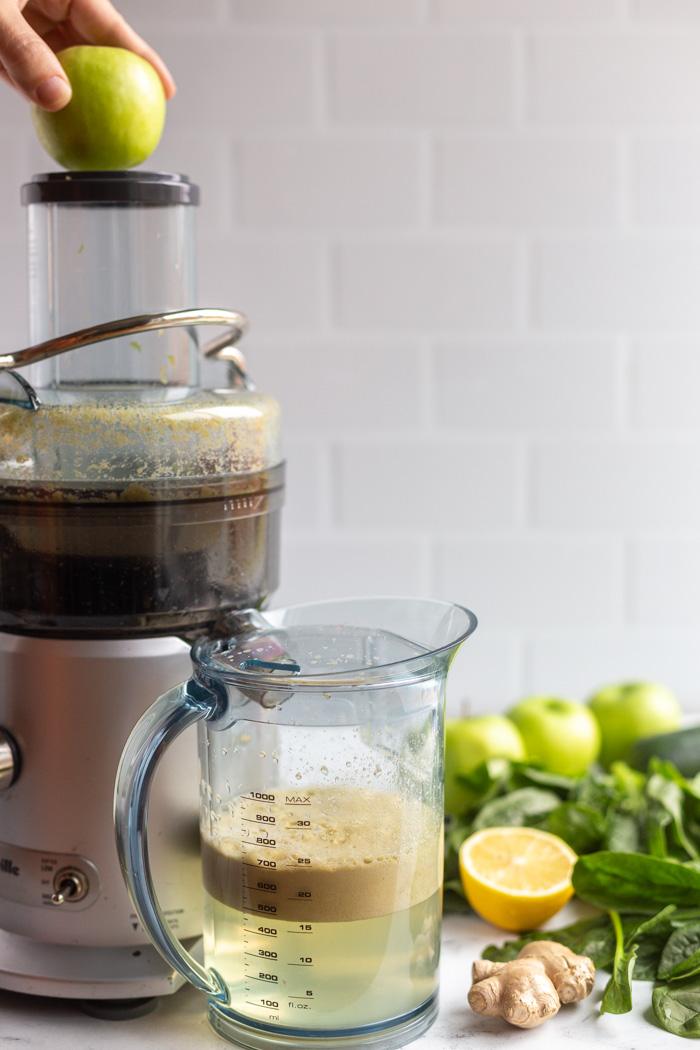 juicer with an apple going in the top to be juiced