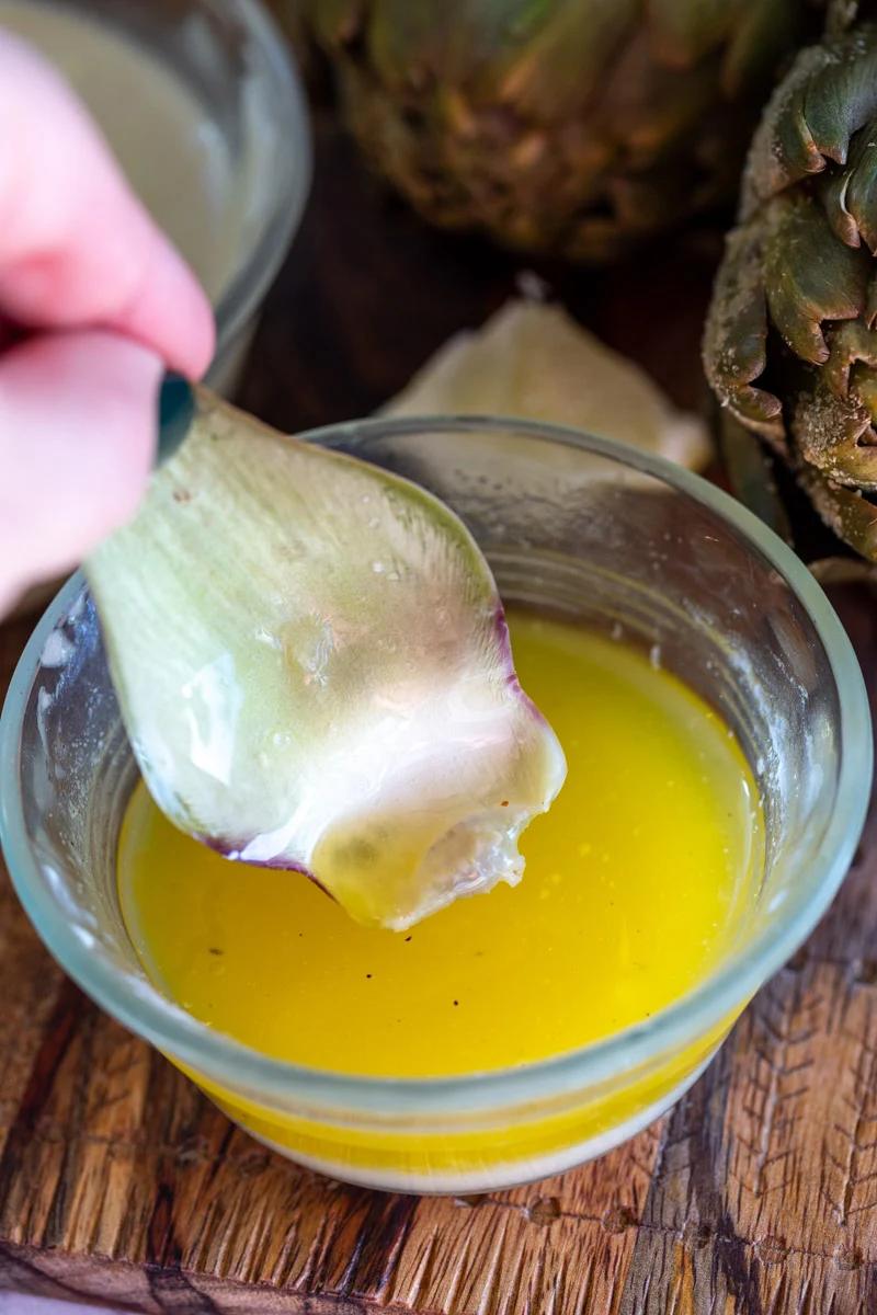 piece of artichoke being dipping in lemon butter