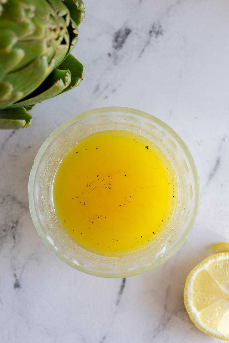 lemon butter sauce with a lemon in one corner of the shot and an artichoke in another corner