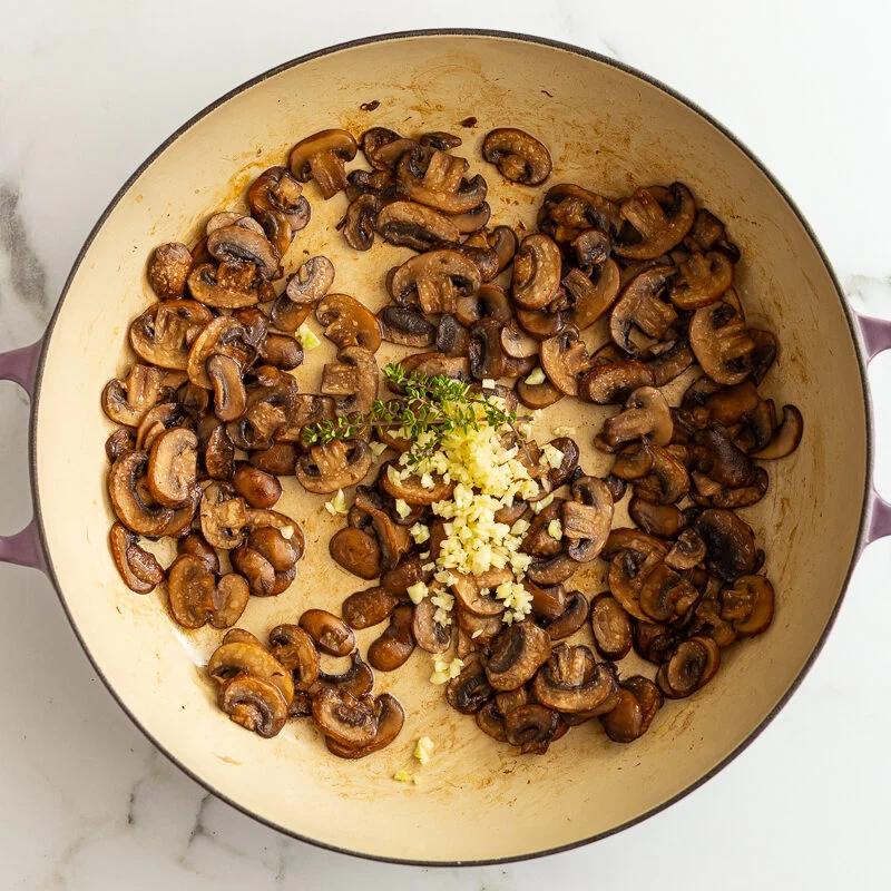 sauteed baby bella mushrooms in a skillet with garlic and herbs