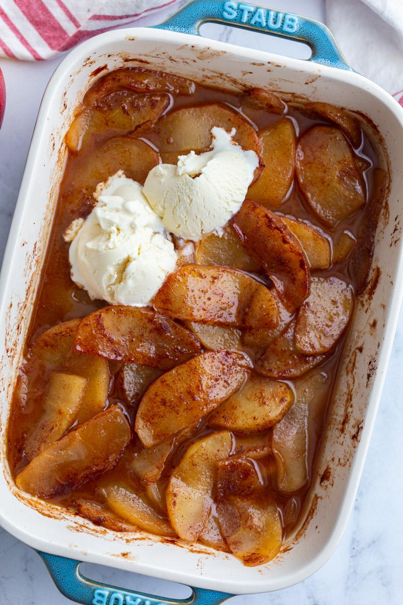 cinnamon apple slices in a baking dish and topped with vanilla ice cream