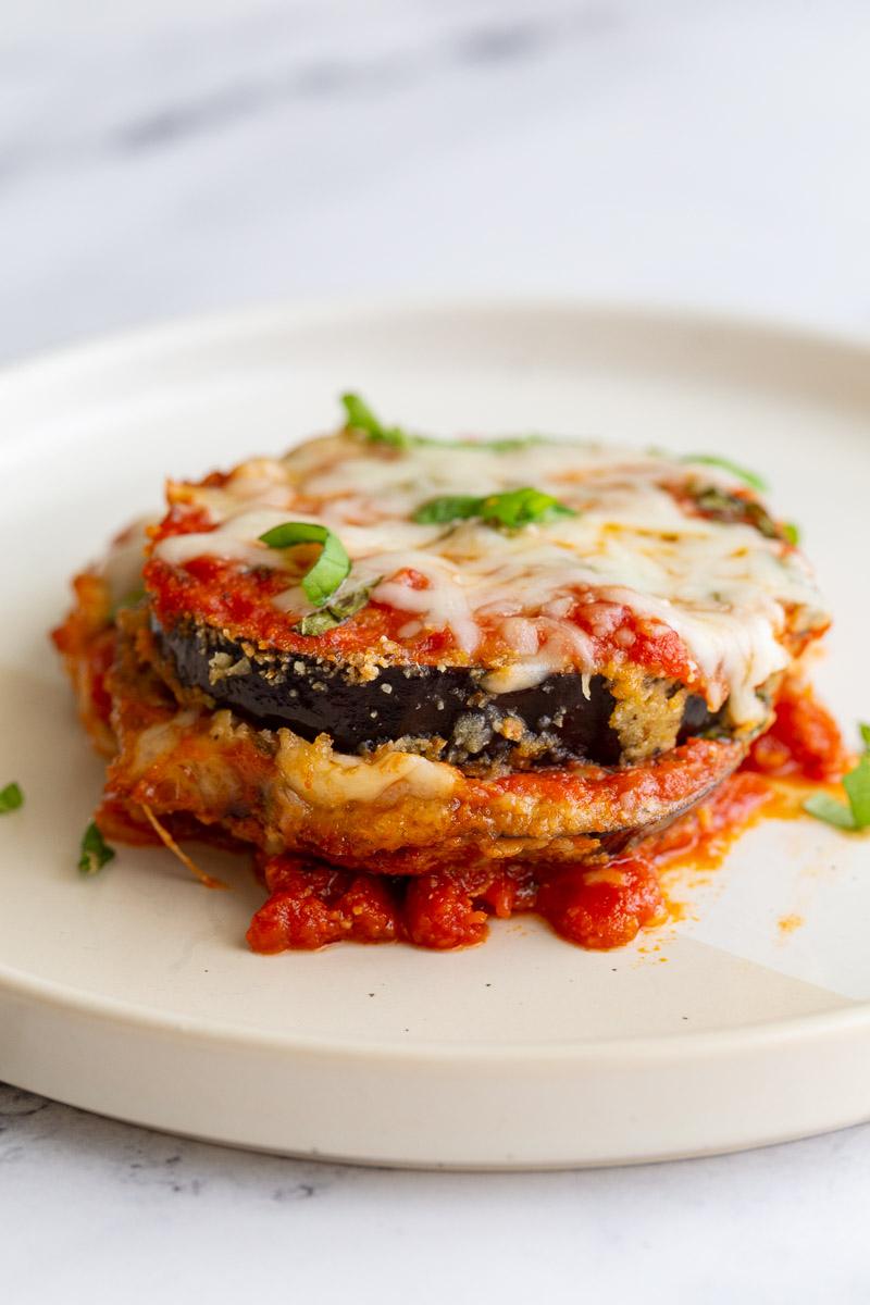 Slice of eggplant parmesan on a white plate.