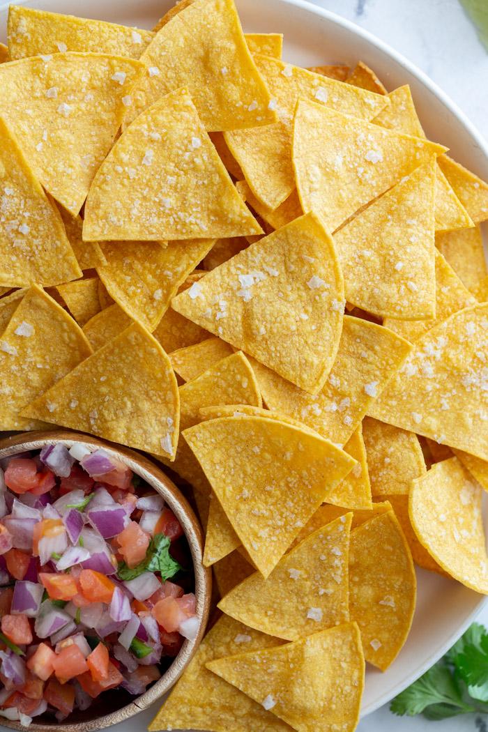 large plate of from-scratch tortilla chips with a bowl of pico de gallo on the plate