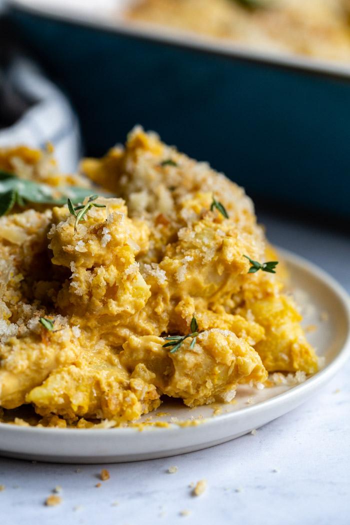 up close shot of baked vegan mac and cheese on a plate and sprinkled with fresh thyme