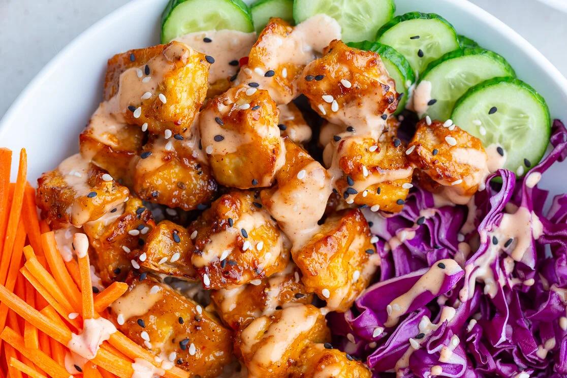 bang bang tofu bowls with rice, cucumber, red cabbage, and carrot sticks