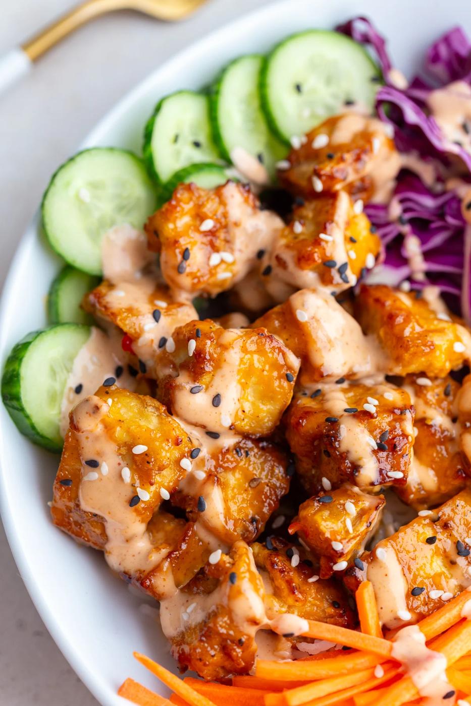 bang bang tofu bowls with rice, cucumber, red cabbage, and carrot sticks
