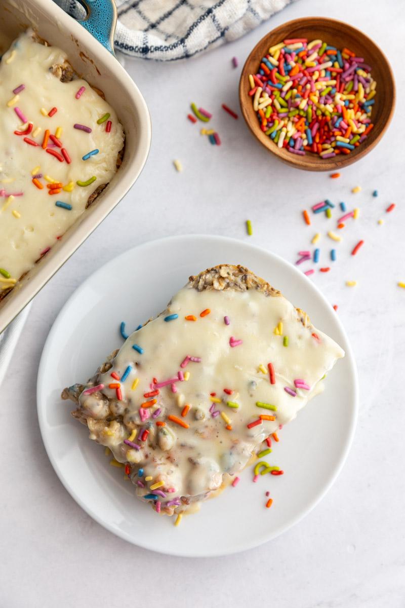 slice of sprinkle baked oats on a small plate with more sprinkles around the scene
