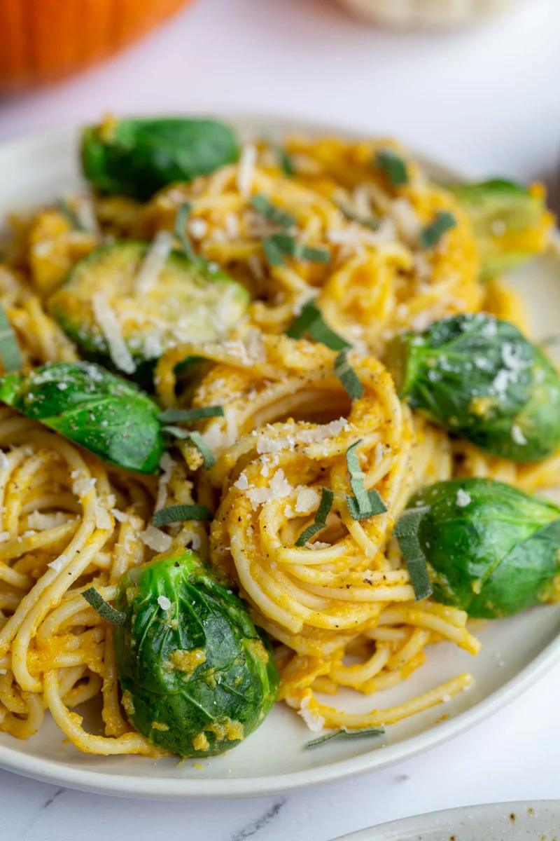 creamy pumpkin pasta spaghetti on a plate with brussels on top