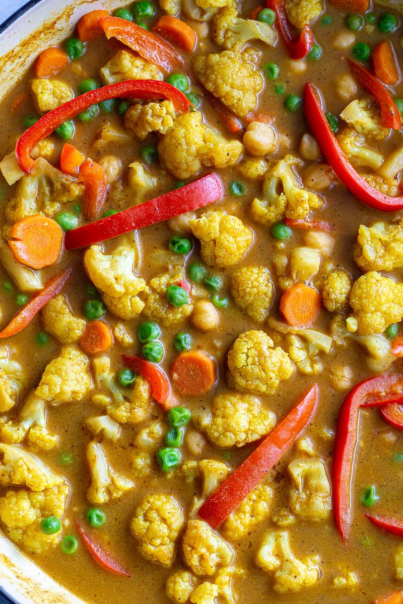 Curry made with cauliflower and veggies cooking in a skillet.