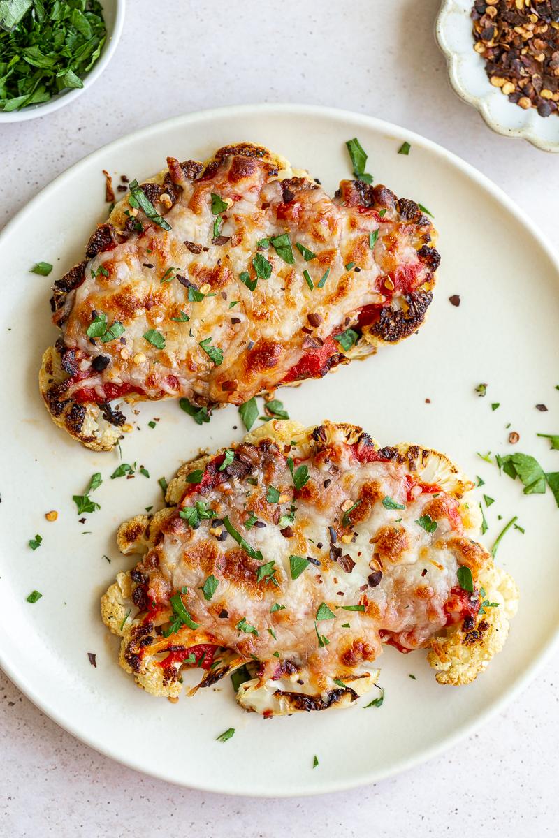 Two slices of cauliflower parmesan on a white plate.