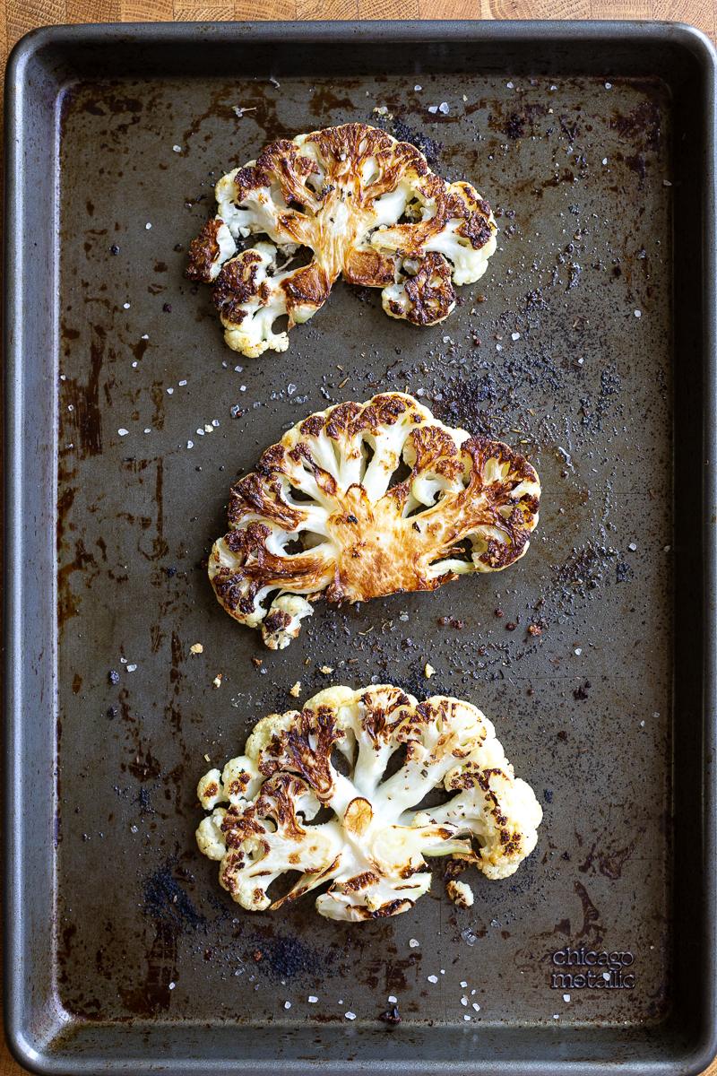 Roasted slices of cauliflower on a sheet pan.