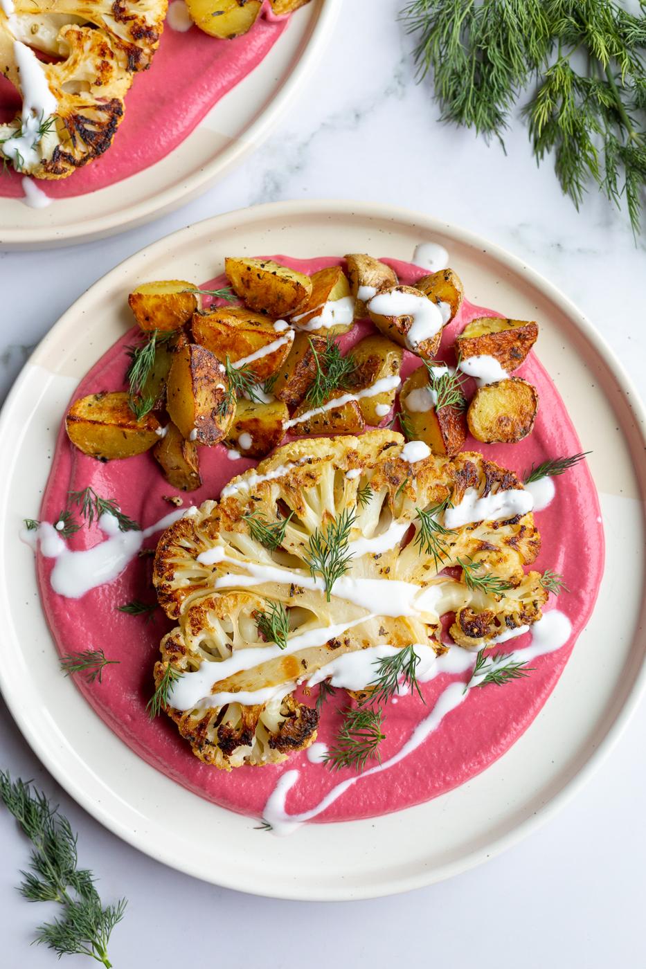 roasted cauliflower steak and roasted baby potatoes on a bed of beet been puree and drizzled with yogurt