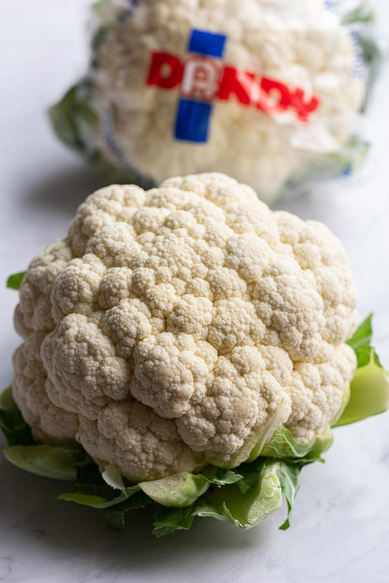 head of cauliflower with a wrapped head of cauliflower in the background with the word "Dandy" on it