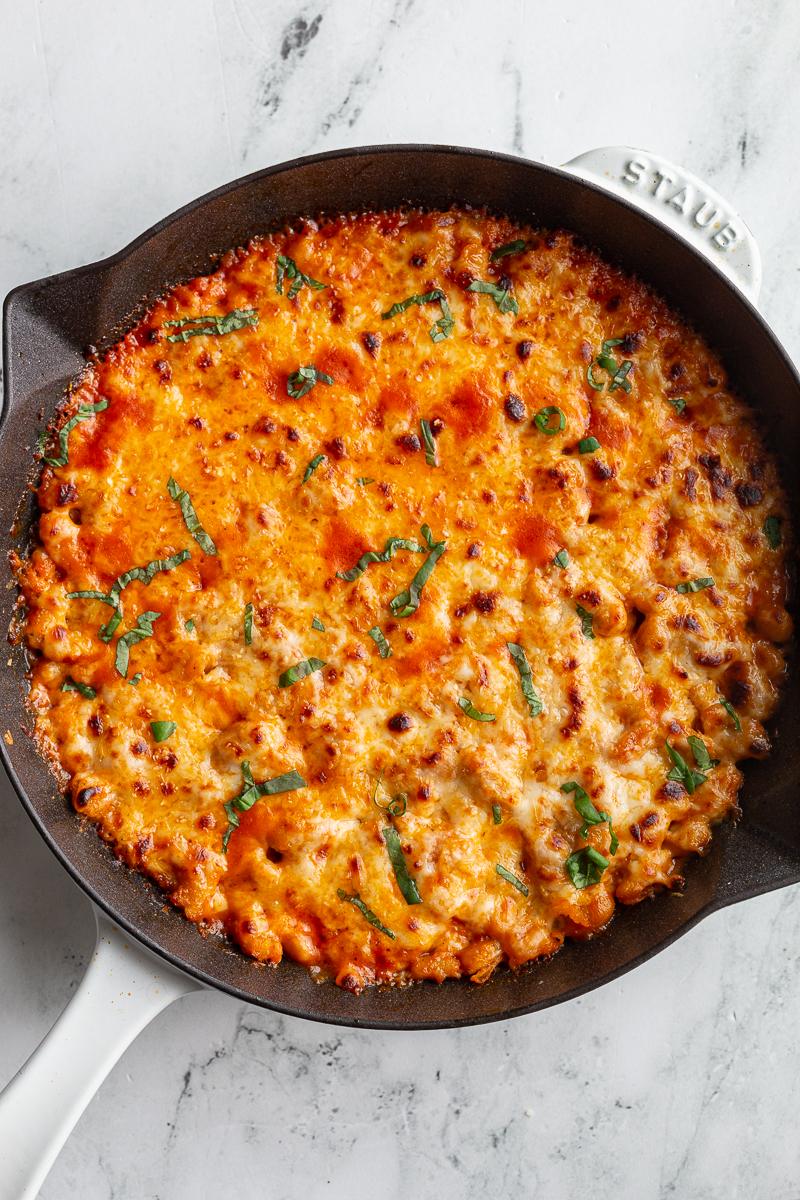 white bean tomato bake topped with lots of white cheese and fresh basil ribbons. In a white cast iron skillet