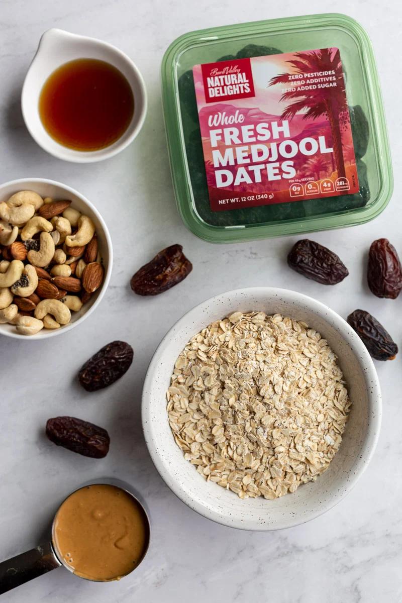 ingredients laid out to make granola bars: oats, dates, maple syrup, nut mix, and peanut butter