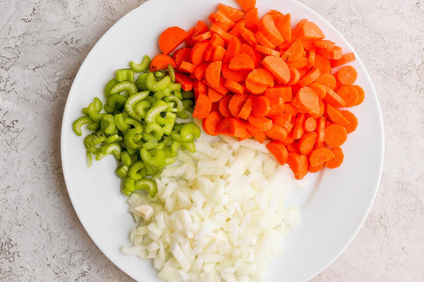 chopped carrot, onion and celery on a white plate