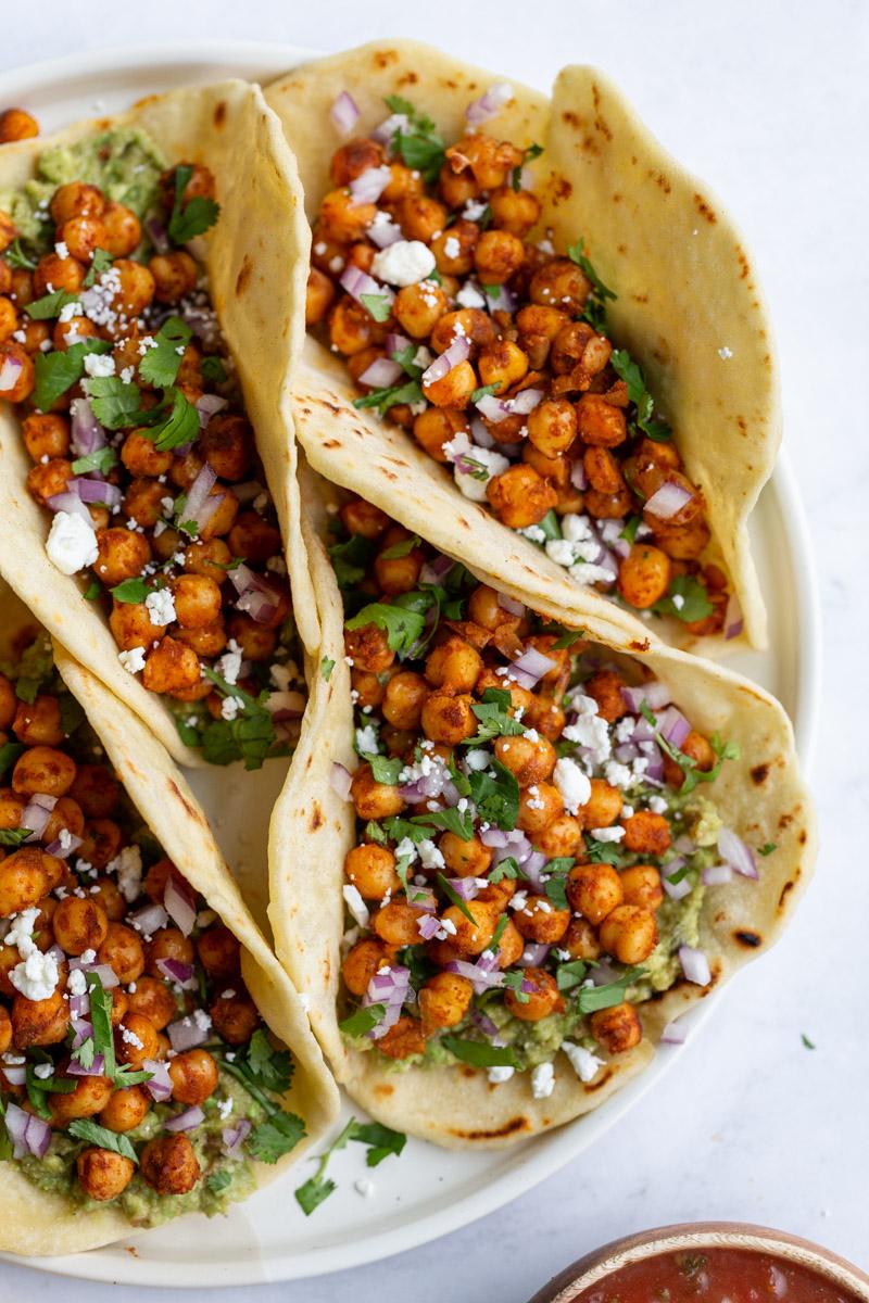 chickpea tacos with cilantro and feta cheese crumbles on a white serving tray