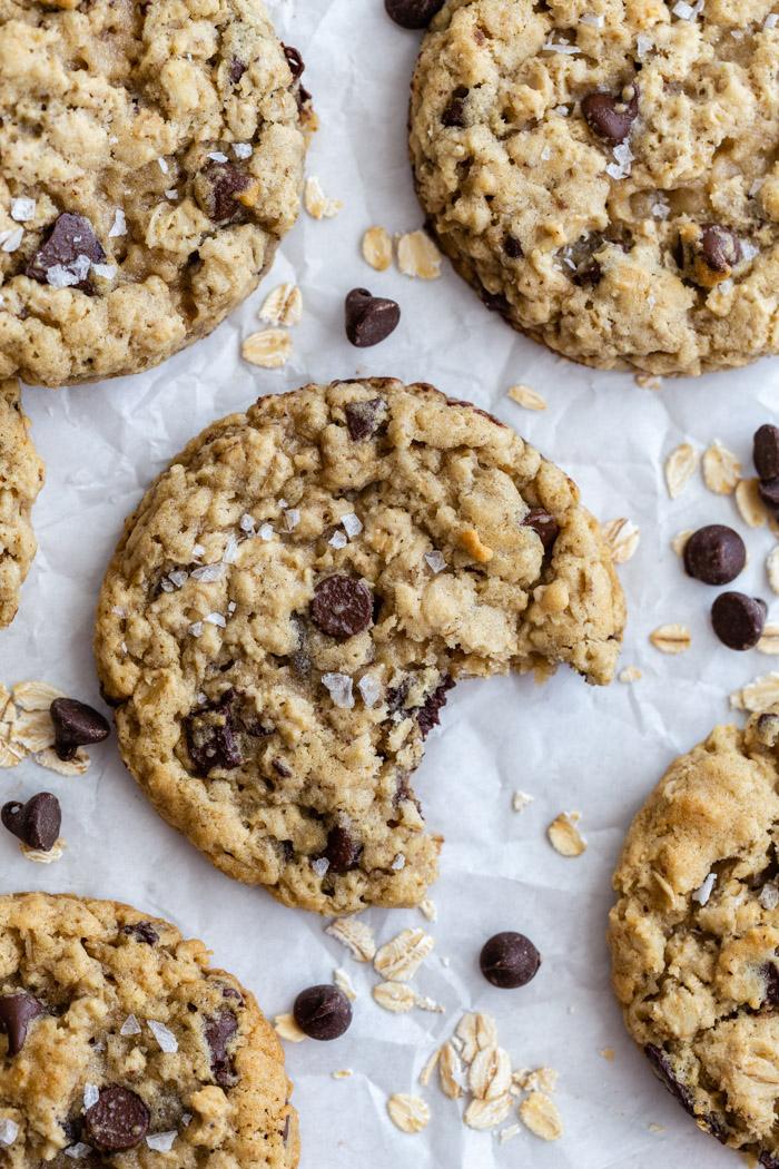 chocolate chip oatmeal cookies on parchment paper with oats and chips surrounding it