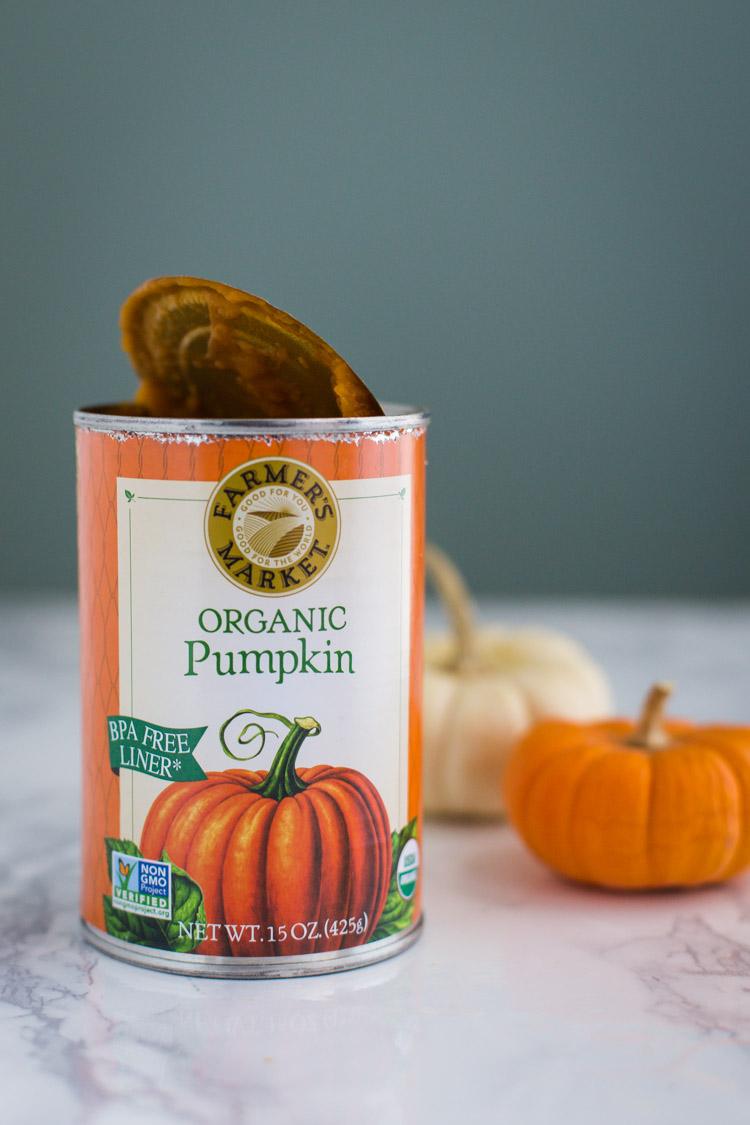 Opened can of farmers market organic pumpkin puree with mini pumpkins in the background