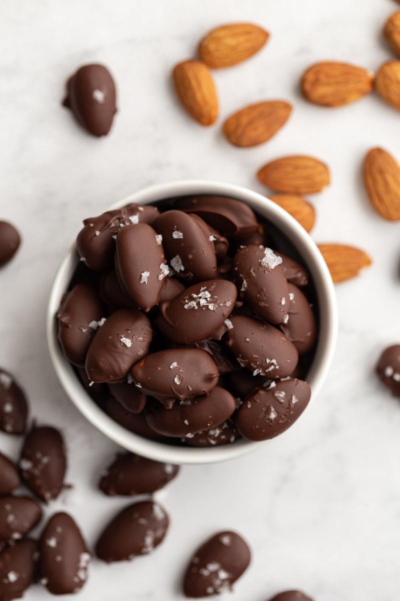 dark chocolate covered almonds in a small white bowl