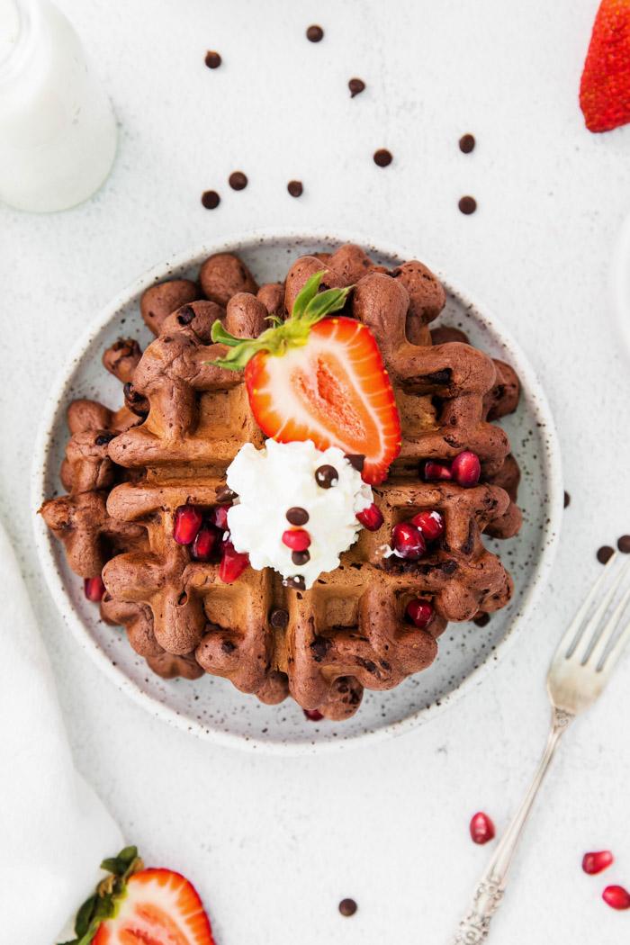 chocolate waffles topped with whipped cream, chocolate chips and fresh fruit
