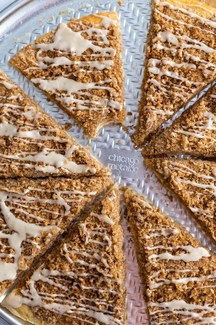 cinnamon sugar dessert pizza cut in slices and topped with a frosting. a bite is taken out of one slice