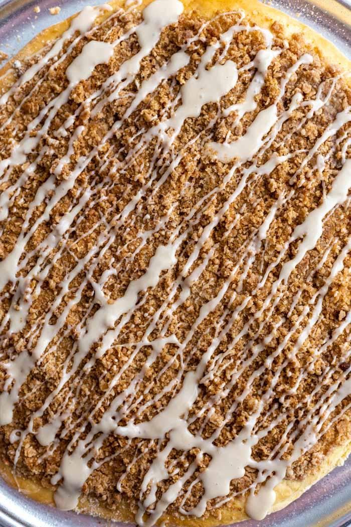 up close shot of large cinnamon sugar dessert pizza on a pizza pan and drizzled with frosting