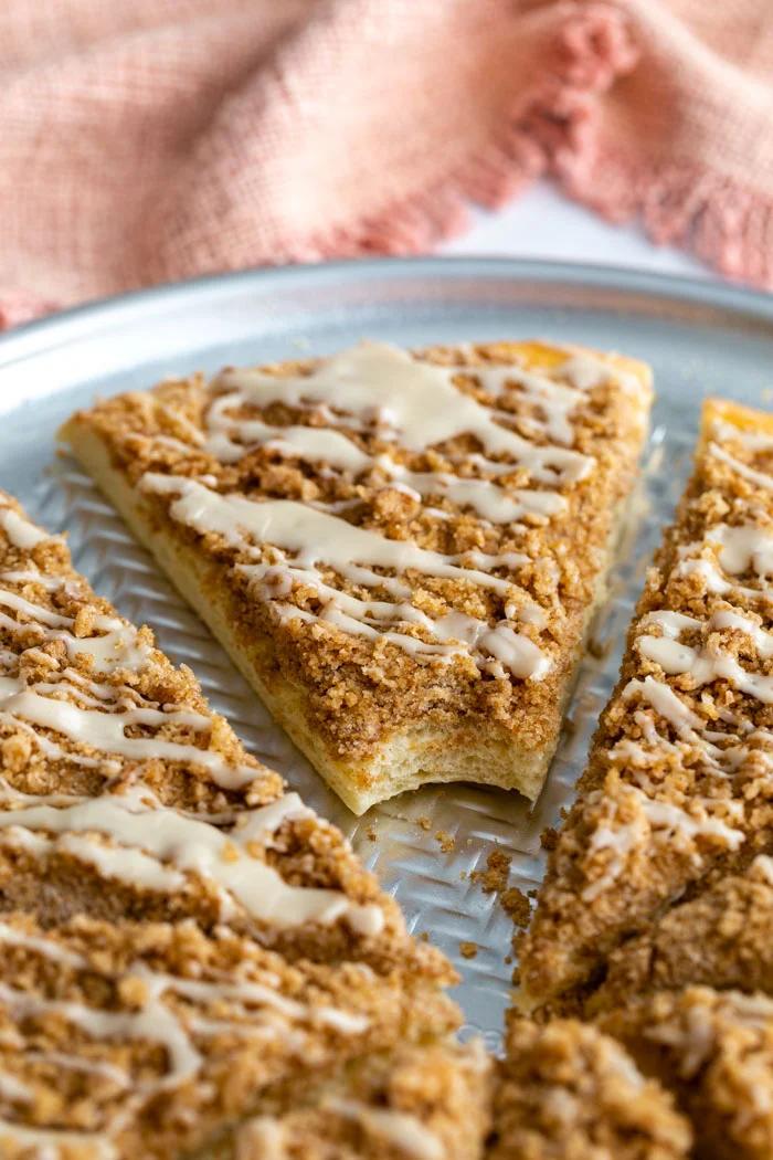 cinnamon sugar dessert pizza cut in slices and topped with a frosting. a bite is taken out of one slice