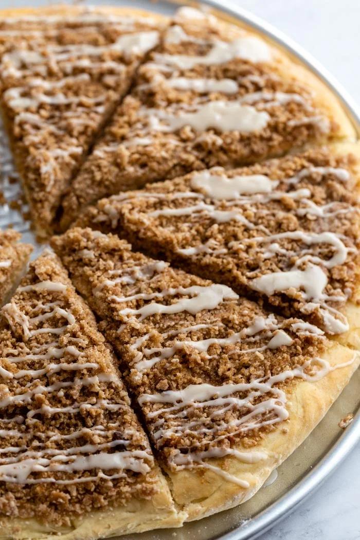 cinnamon sugar dessert pizza cut in slices and topped with a frosting.