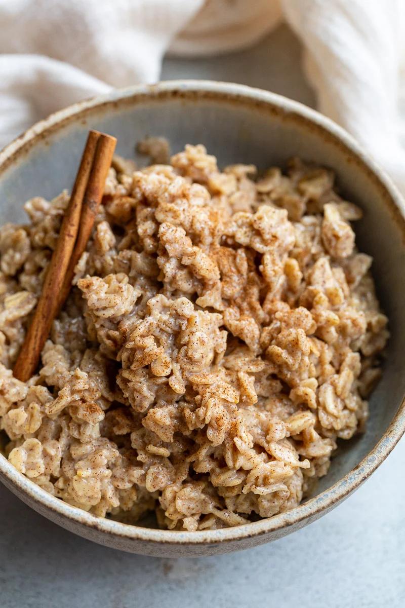 Cinnamon oatmeal in a bowl with a cinnamon stick.