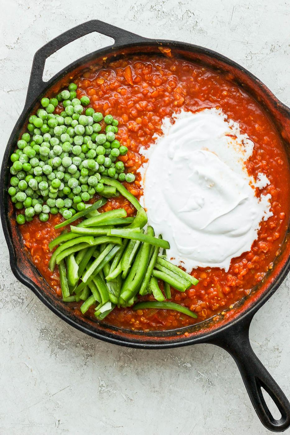 Adding peas, bell pepper and coconut milk to lentils.