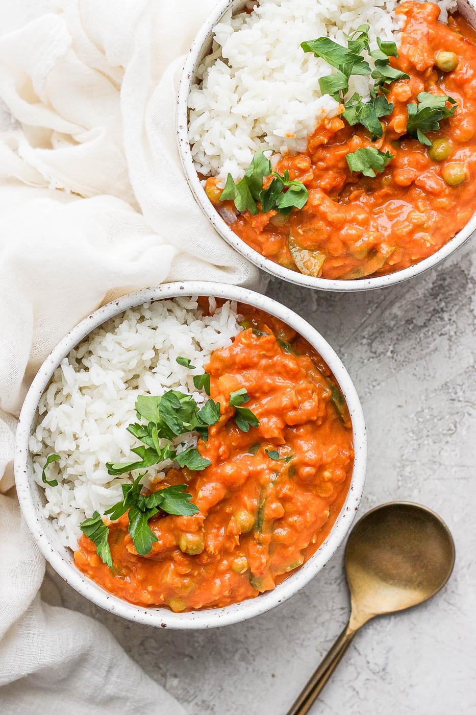 Two bowls of lentil curry served with coconut rice.