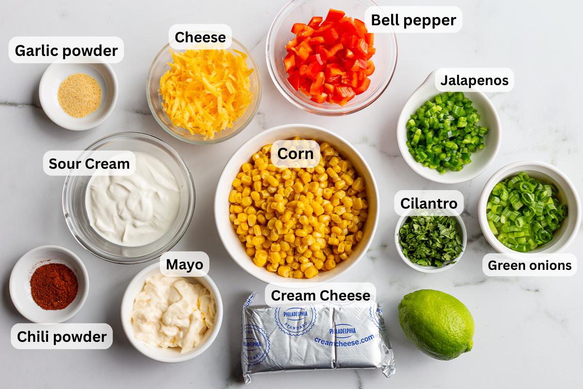 labeled ingredients needed for cream cheese corn dip including cream cheese, corn, bell pepper, jalapeno, mayo, lime juice, cheese, and cilantro