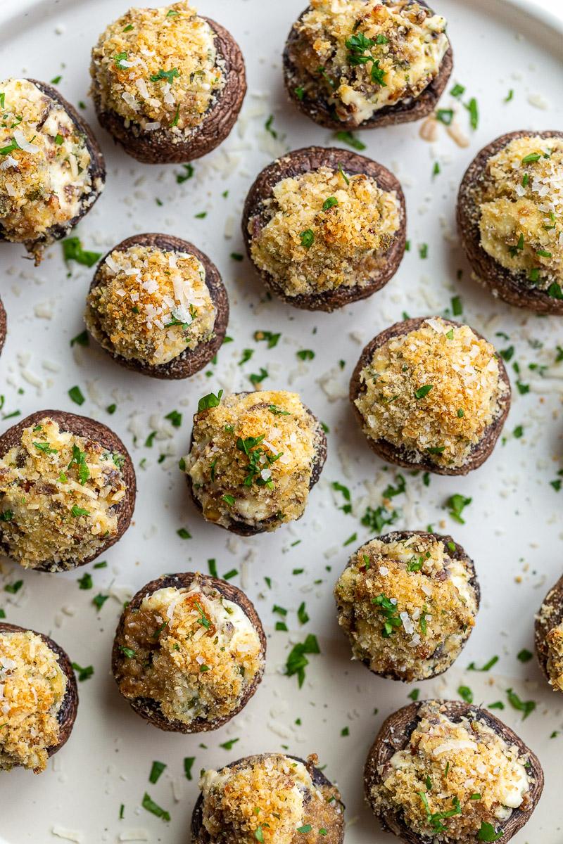Stuffed mushrooms garnished with fresh parsley on a white plate.