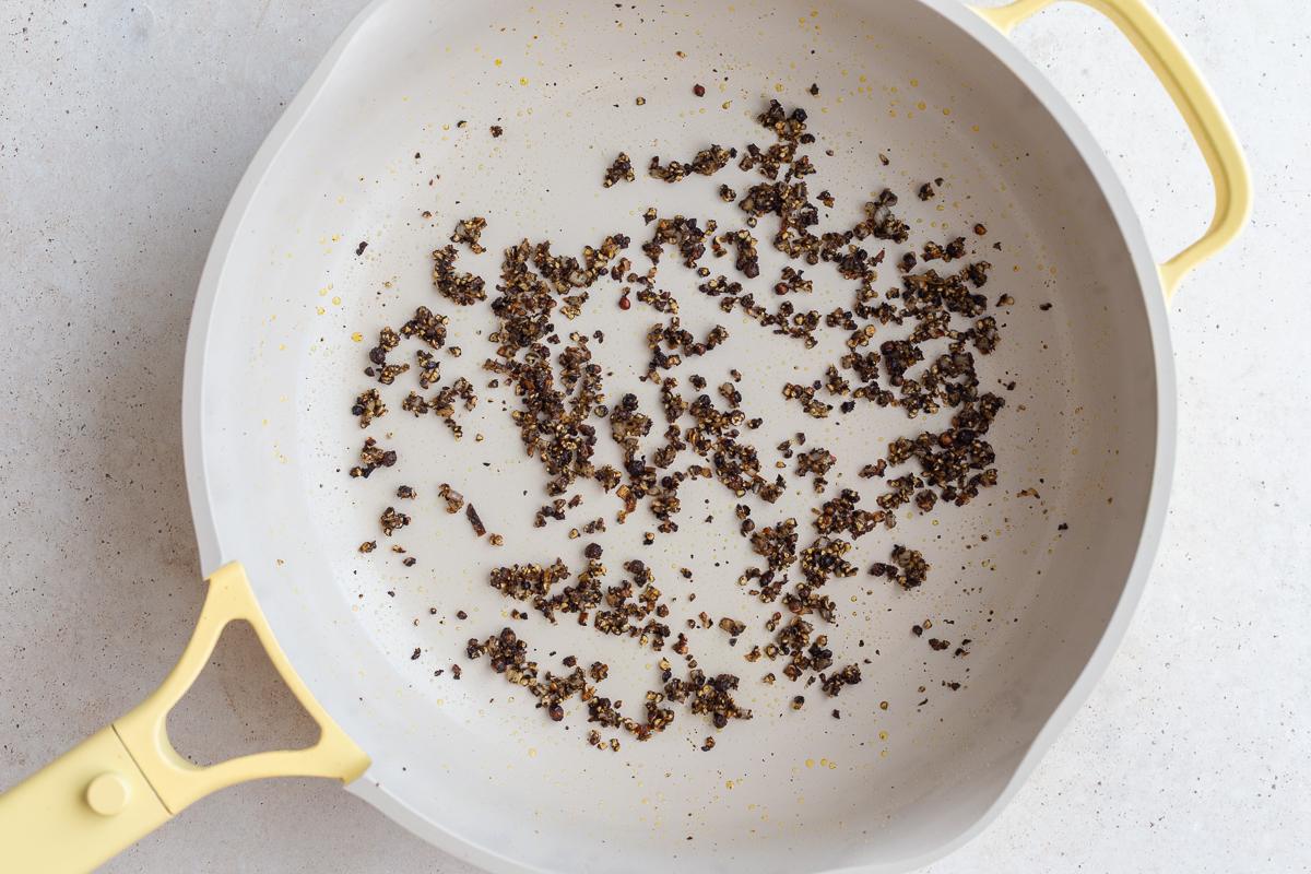 diced shallot and ground up peppercorns in a large skillet