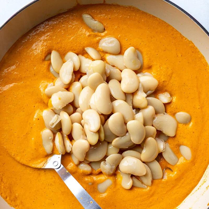 romesco sauce in a skillet with beans poured on top before theyve been stirred in