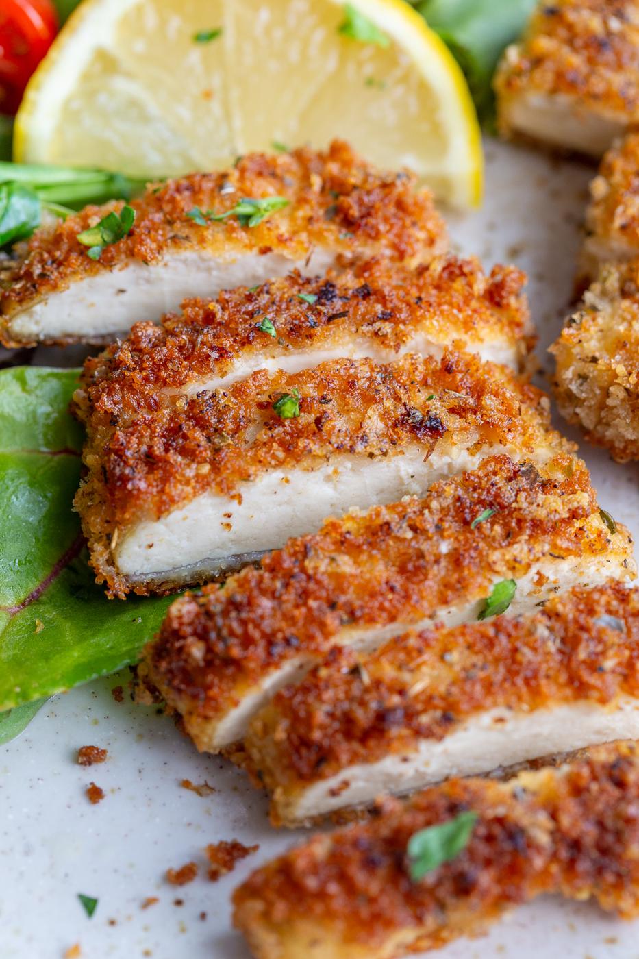 A tofu cutlet sliced into pieces near a lemon wedge.