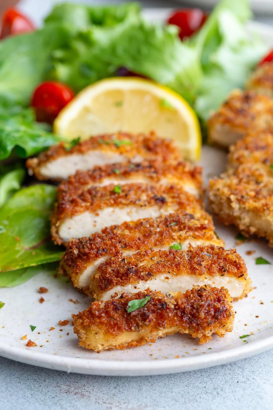 A tofu cutlet sliced into pieces near a lemon wedge.