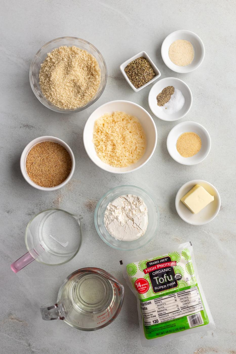 Small bowls with breadcrumbs and seasonings near a package of tofu.