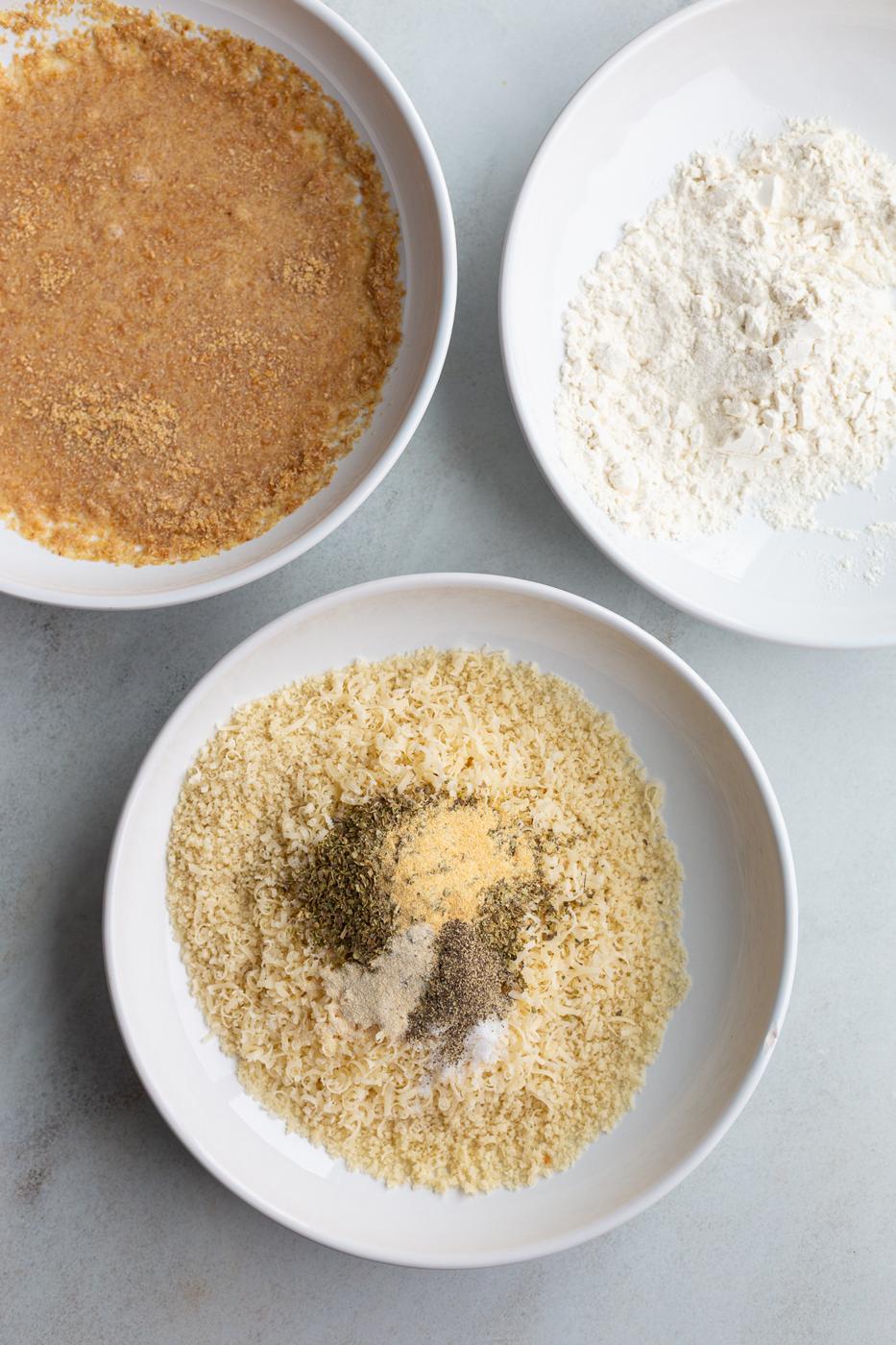 Three bowls with a flax and water mixture, flour and one with breadcrumbs and seasonings.