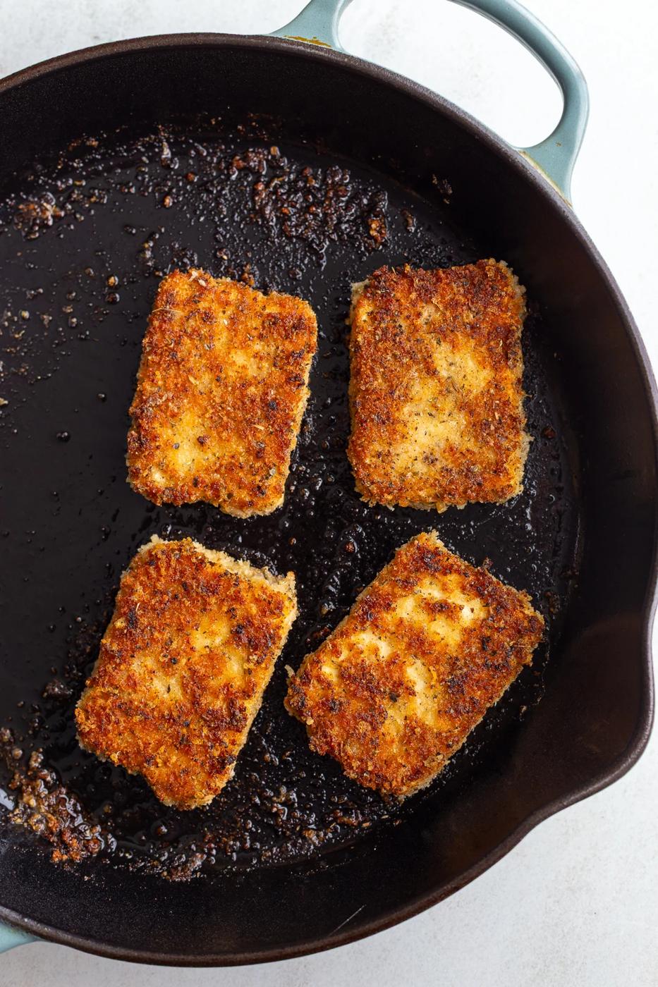 Cooking tofu cutlets in a large skillet with oil.